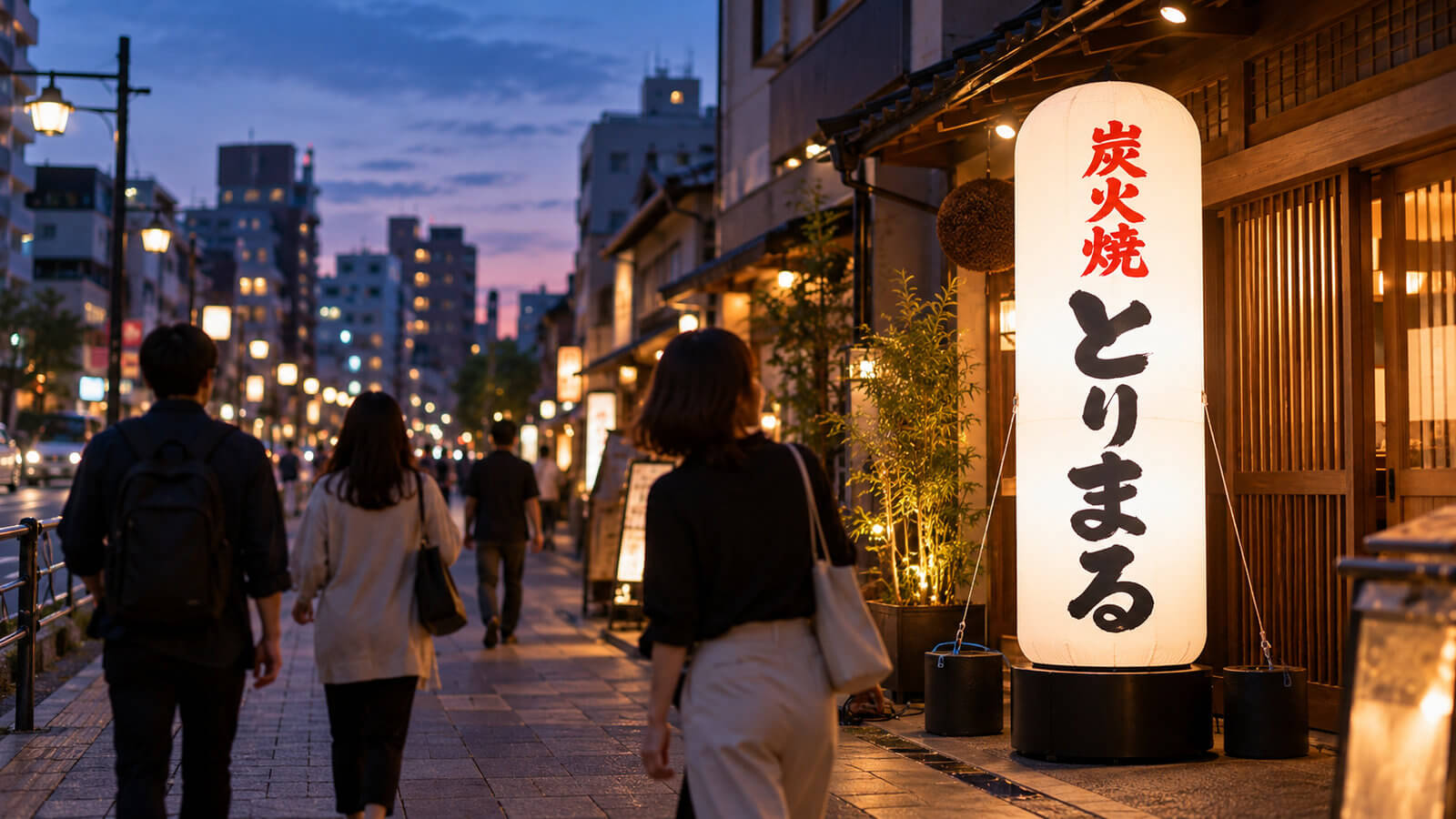夕暮れの商店街で、飲食店の入口横に置かれた高さ3mの円柱型エアー看板が内側から明るく光り、通行人が振り返っている様子