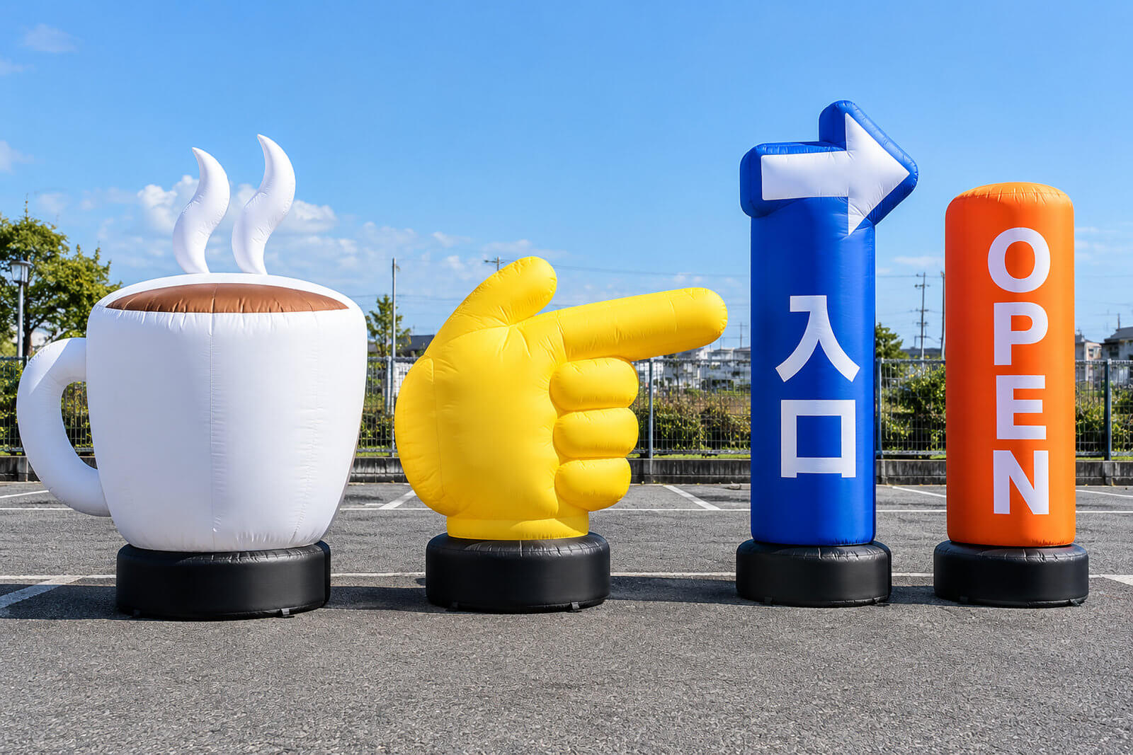 コーヒーカップの形、指さしをする手の形、上部に矢印の付いた円柱型など、さまざまな形のエアー看板が屋外に並んでいる様子