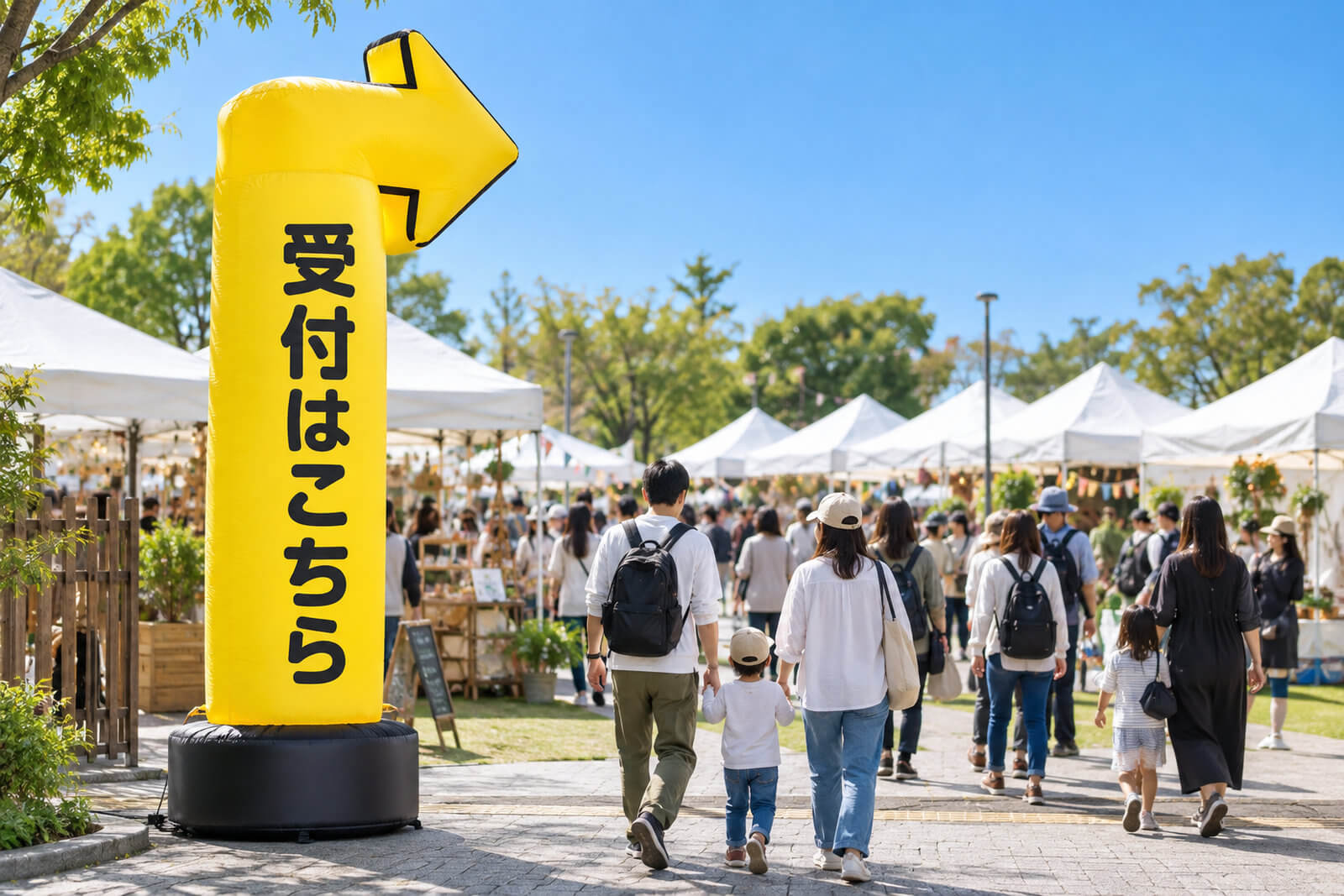 地域のマルシェ会場の入口に立つ高さ4mのエアー看板。上部に矢印の形があり「受付はこちら」と表示されている
