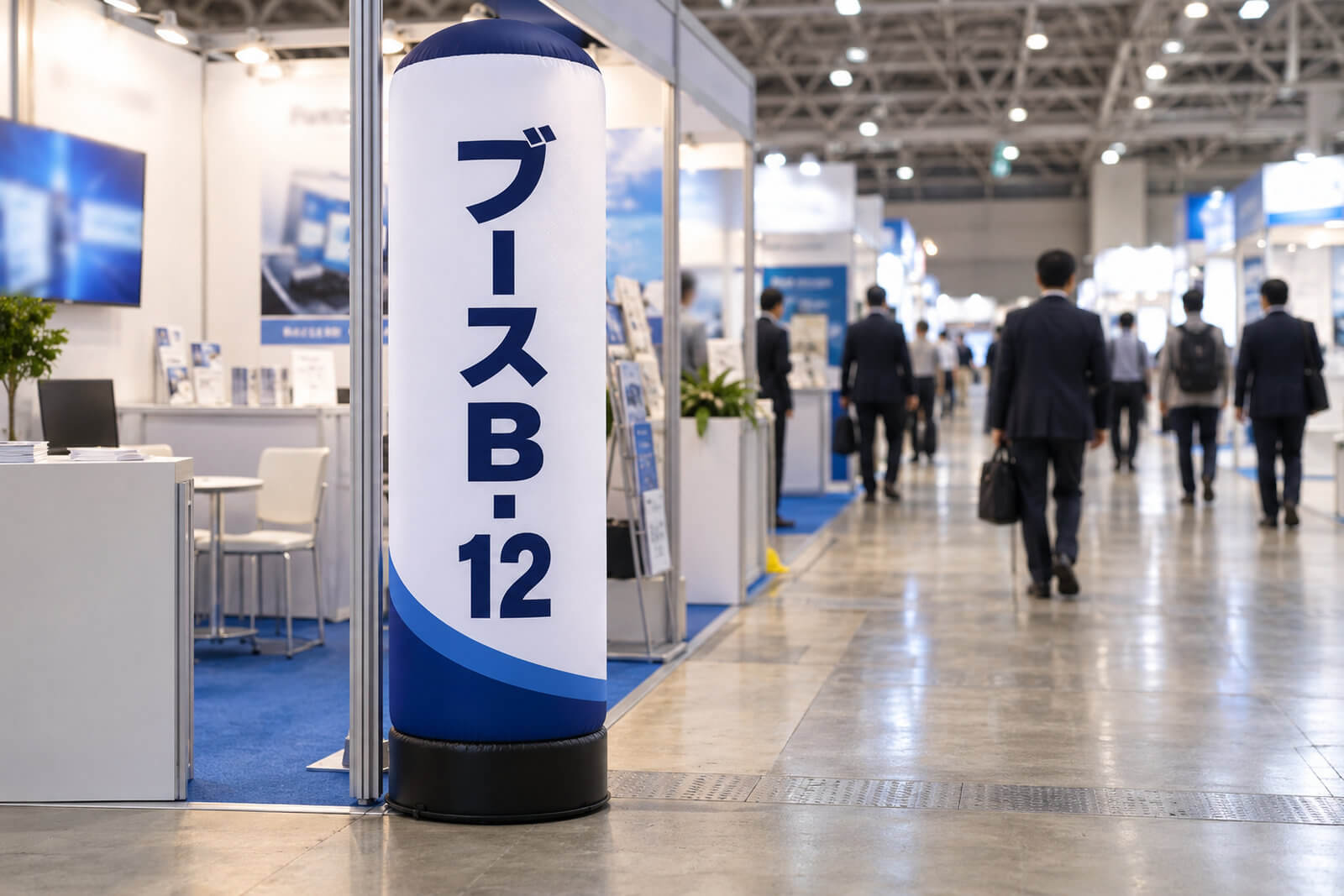 屋内の展示会場の出展ブースの角に置かれた高さ1.5mのエアー看板。会社名とブース番号が入っている