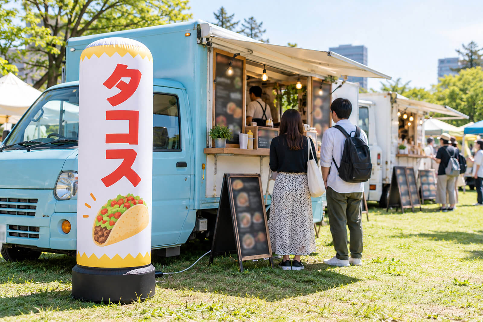 公園のイベントに出店したキッチンカーの横に置かれた高さ2mのエアー看板。店名と料理のイラストが入っている
