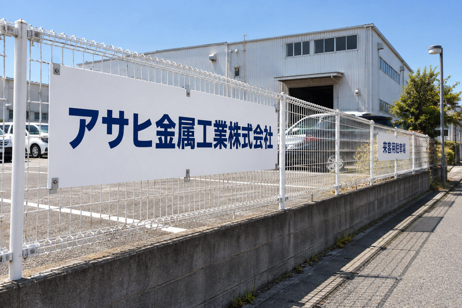 工場のフェンスと駐車場に取り付けた社名入りのアルミ複合板プレート看板