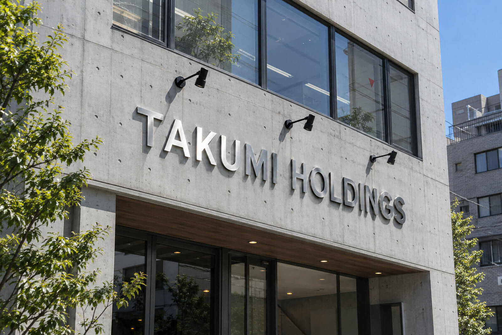 ビルの外壁に取り付けたステンレス切文字の社名とスポットライト