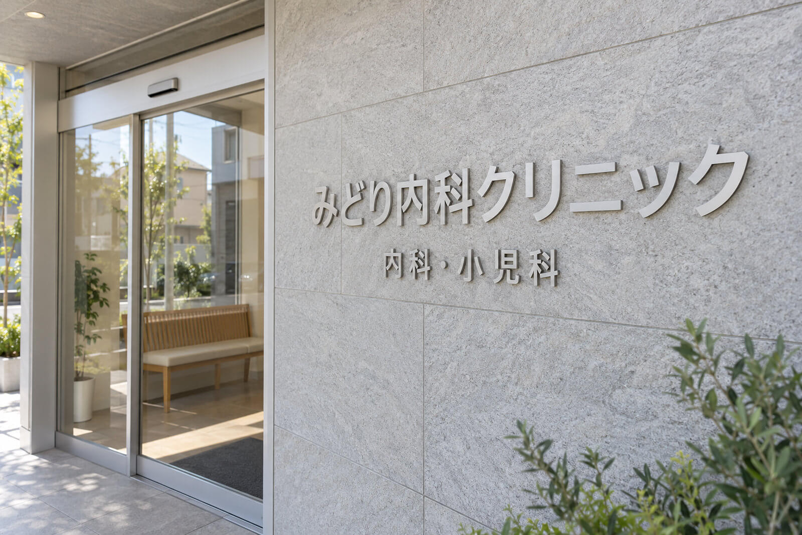 クリニックの入口壁面に取り付けたビーズブラスト仕上げのステンレス切文字の医院名