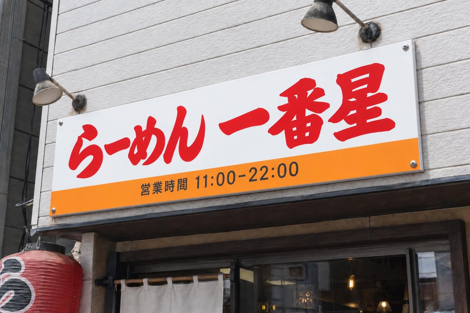 同じ看板のシートを貼り替えて、鮮やかな色に戻った店舗のプレート看板