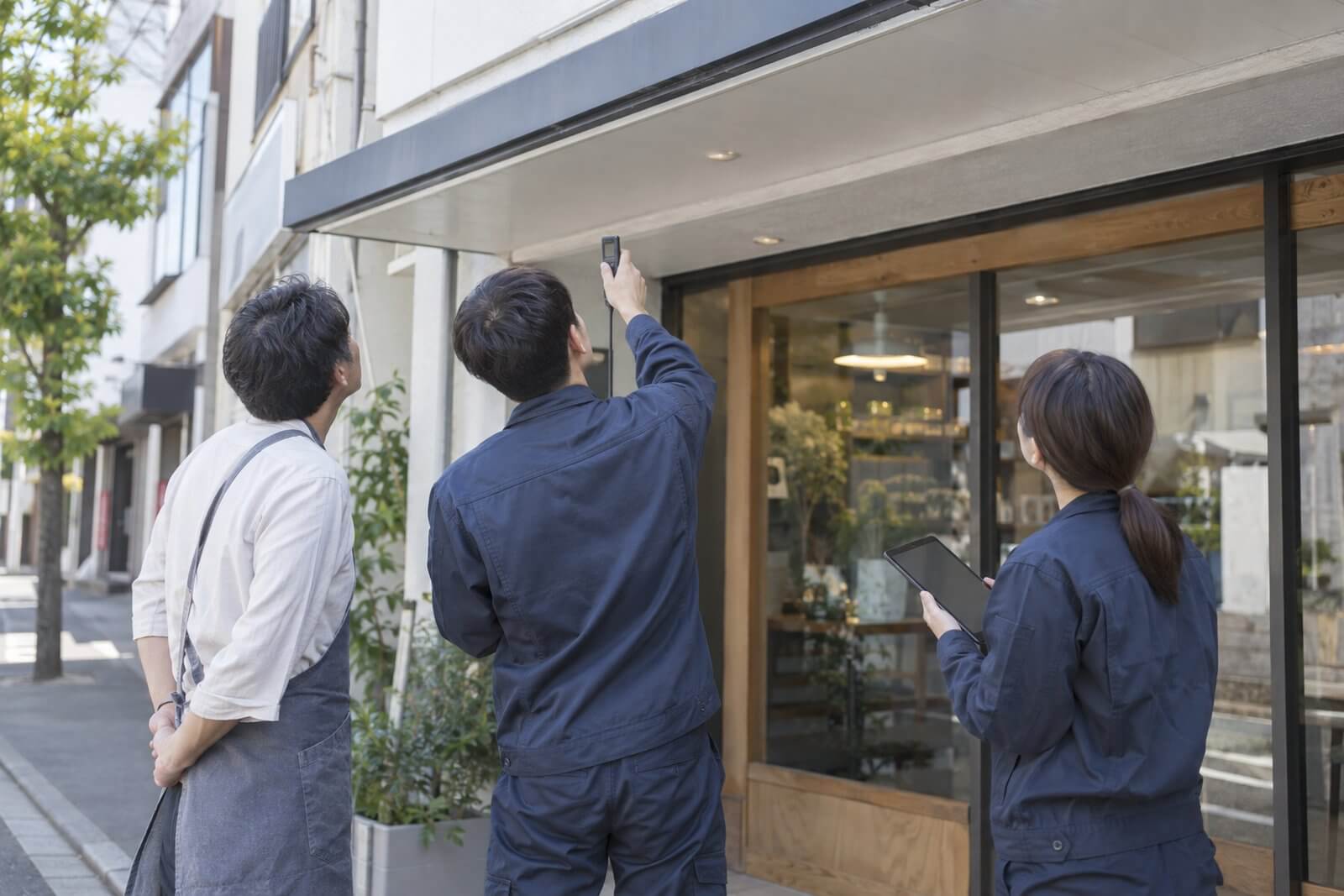 施工スタッフが店舗の軒下の幅をレーザー距離計で測っている様子