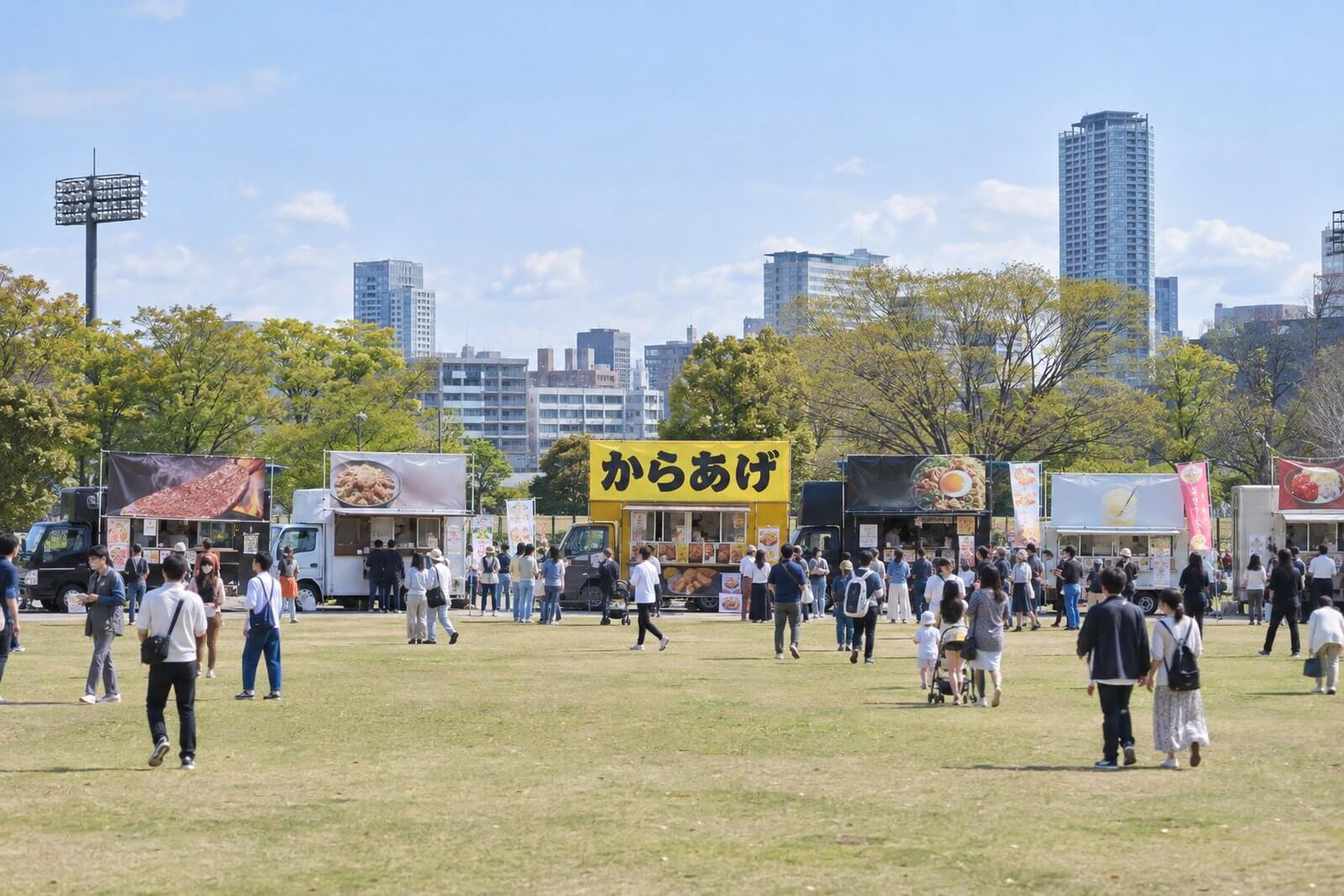 イベント会場で並ぶキッチンカーの中で遠くからでも読める大きな文字の幕を掲げたキッチンカー