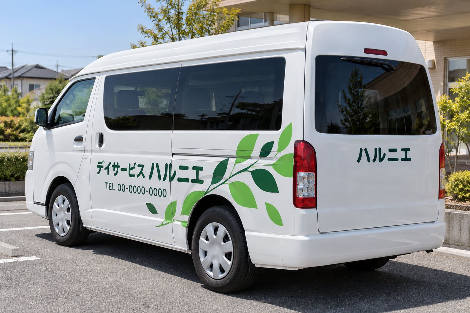 福祉車両の側面と後ろに、施設名とロゴ、電話番号をシートで大きく貼った送迎車