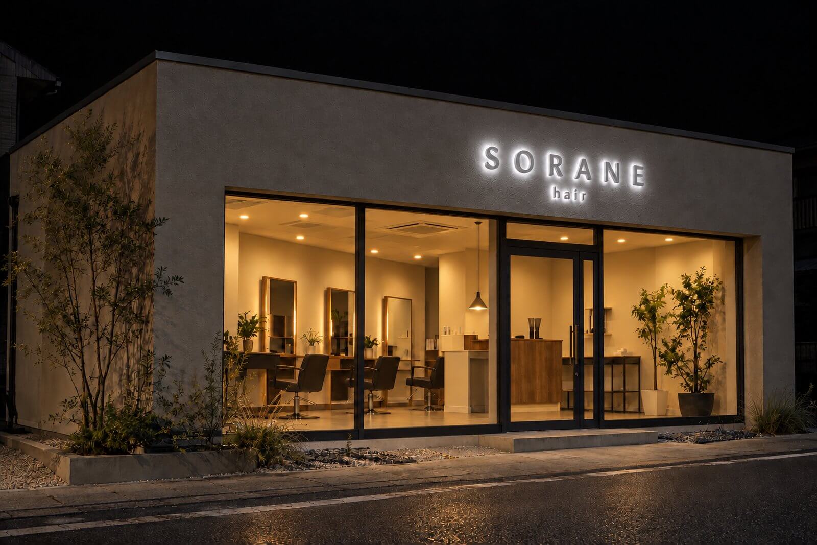 同じヘアサロンの夜の外観。店名の立体文字の裏から光がもれ、壁に文字が浮かび上がって見える