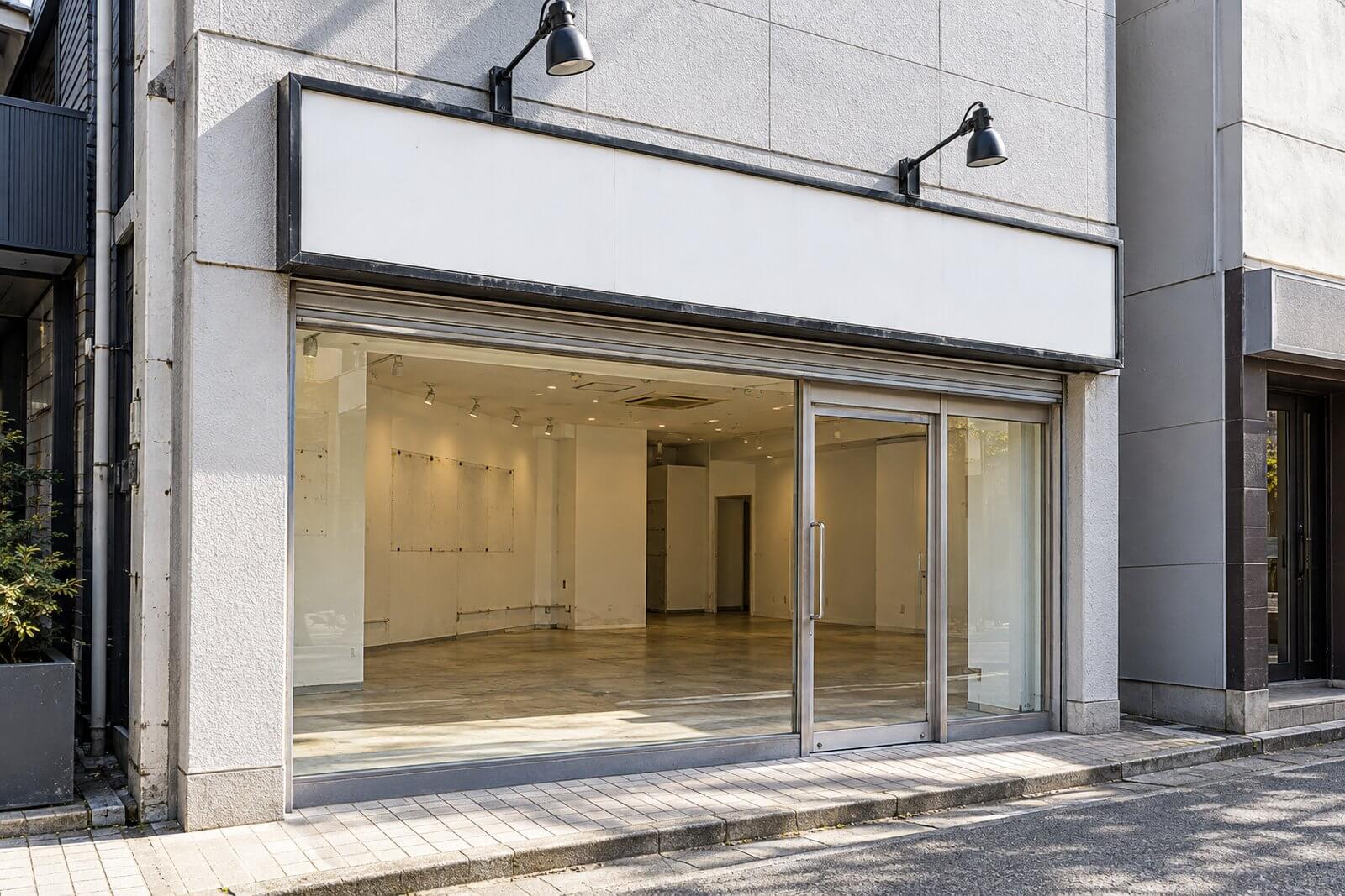 空き店舗の入口の上に前のお店の看板の枠と照明が残り、面は白い板でふさがれている居抜き物件の外観